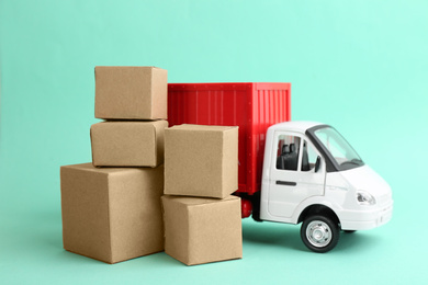 Photo of Truck model and carton boxes on turquoise background. Courier service