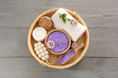 Sea salt and different spa products on light grey wooden table, top view