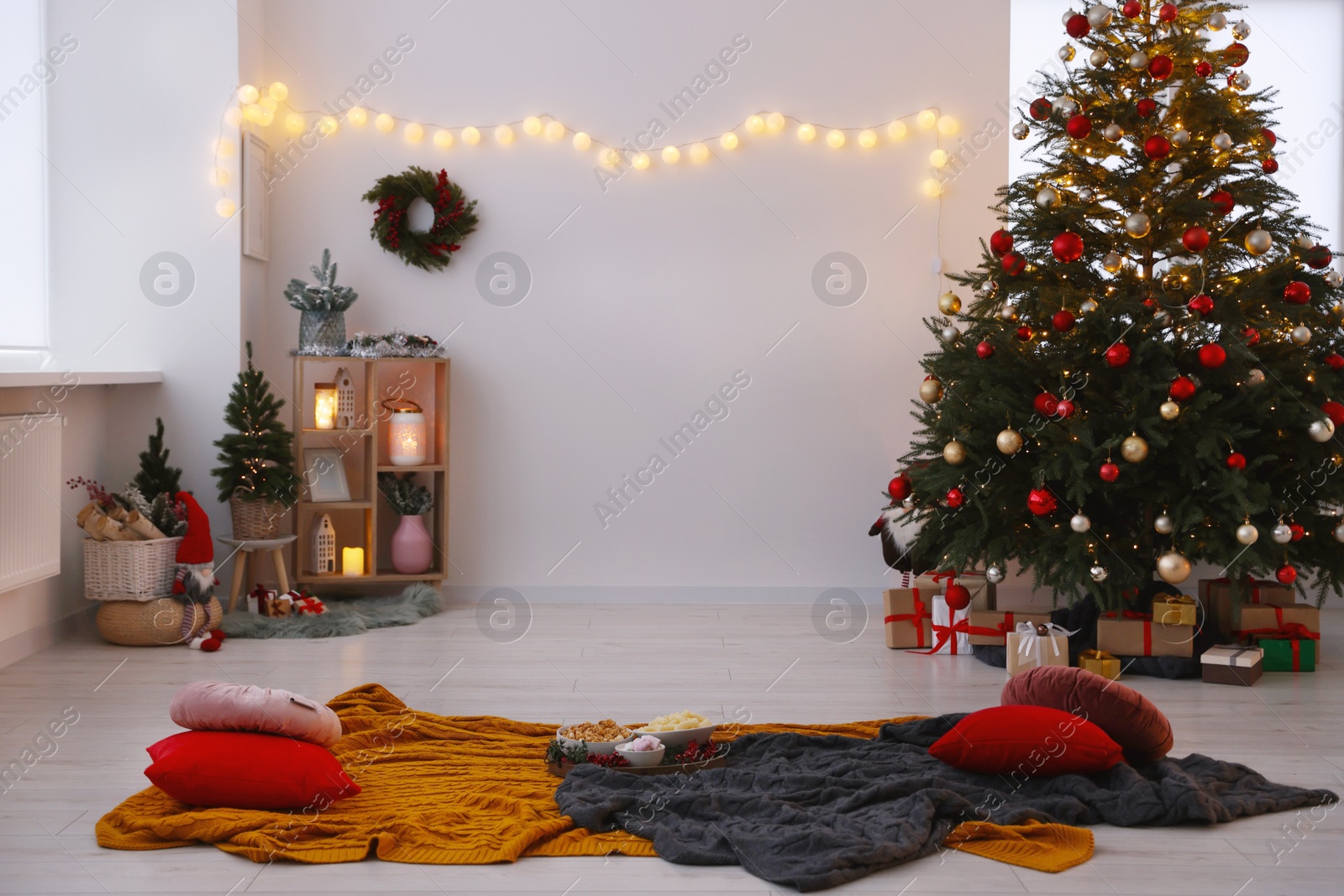 Photo of Cosy TV area with beautiful fir tree, snacks, Christmas gifts and accessories in room