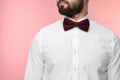 Photo of Man in shirt and bow tie on pink background, closeup