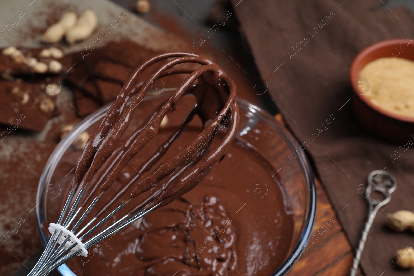 Photo of Whisk with chocolate cream above bowl, closeup