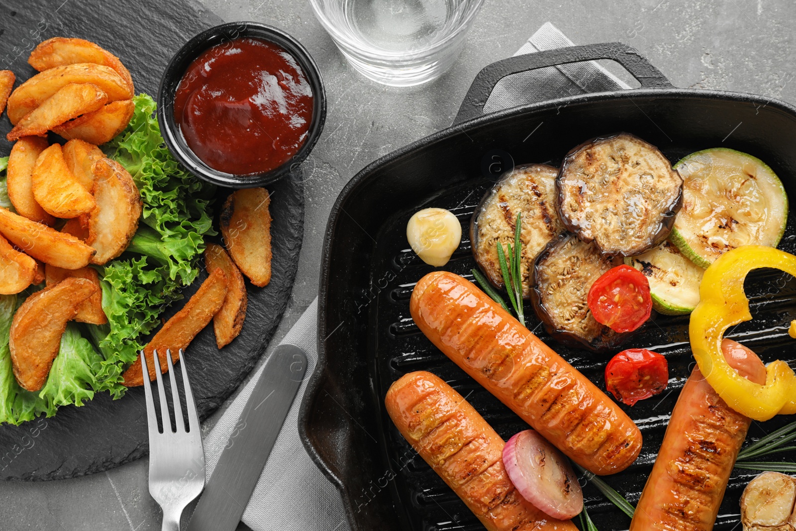Photo of Delicious grilled sausages and vegetables on grey table, flat lay