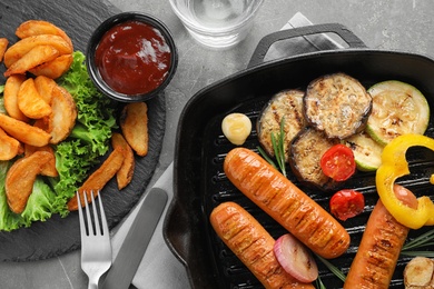 Photo of Delicious grilled sausages and vegetables on grey table, flat lay