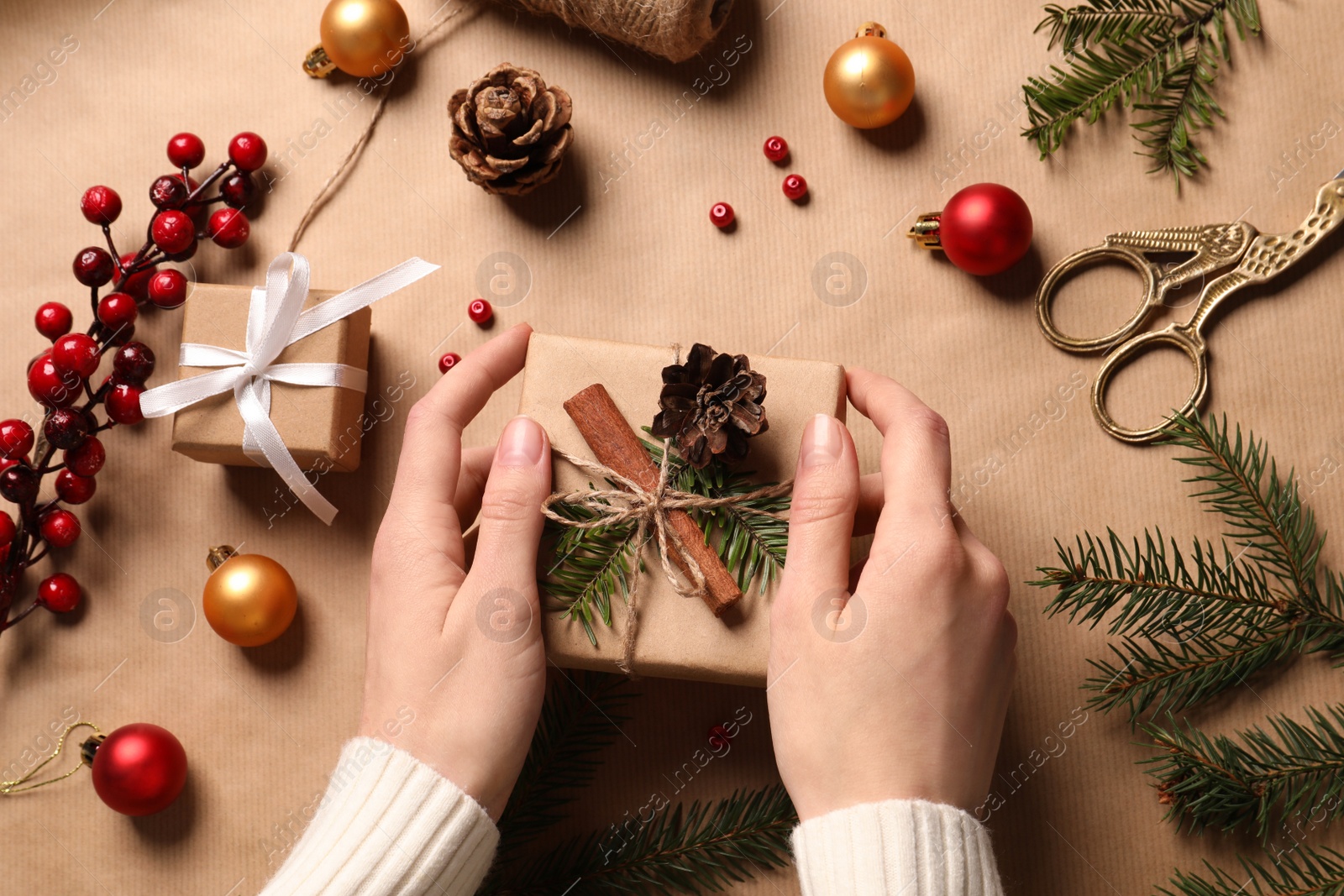 Photo of Woman decorating gift box on wrapping paper, top view. Christmas present