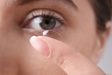 Young woman putting contact lens in her eye, closeup