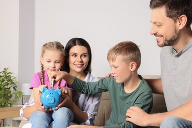 Photo of Happy family with money and piggy bank at home