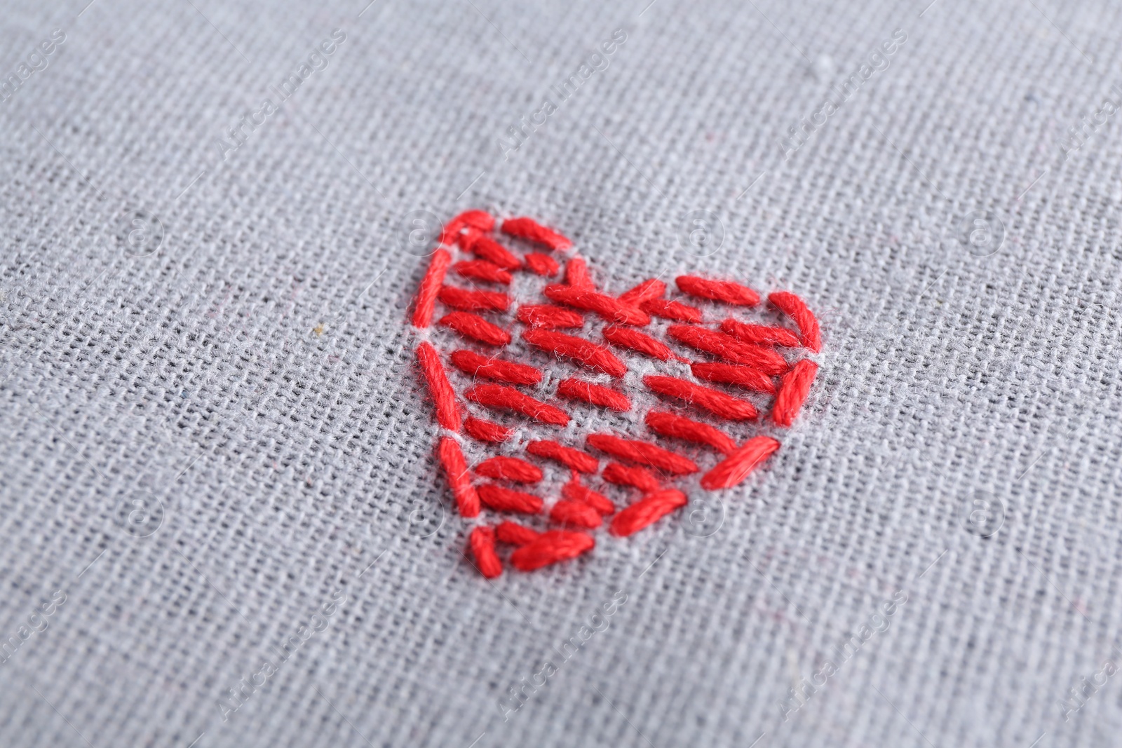 Photo of Embroidered red heart on gray cloth, closeup