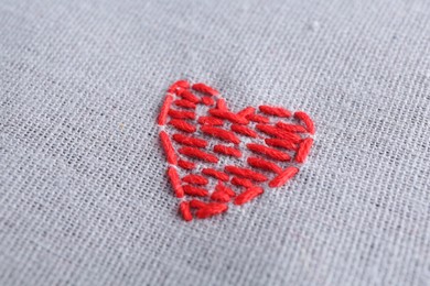 Photo of Embroidered red heart on gray cloth, closeup