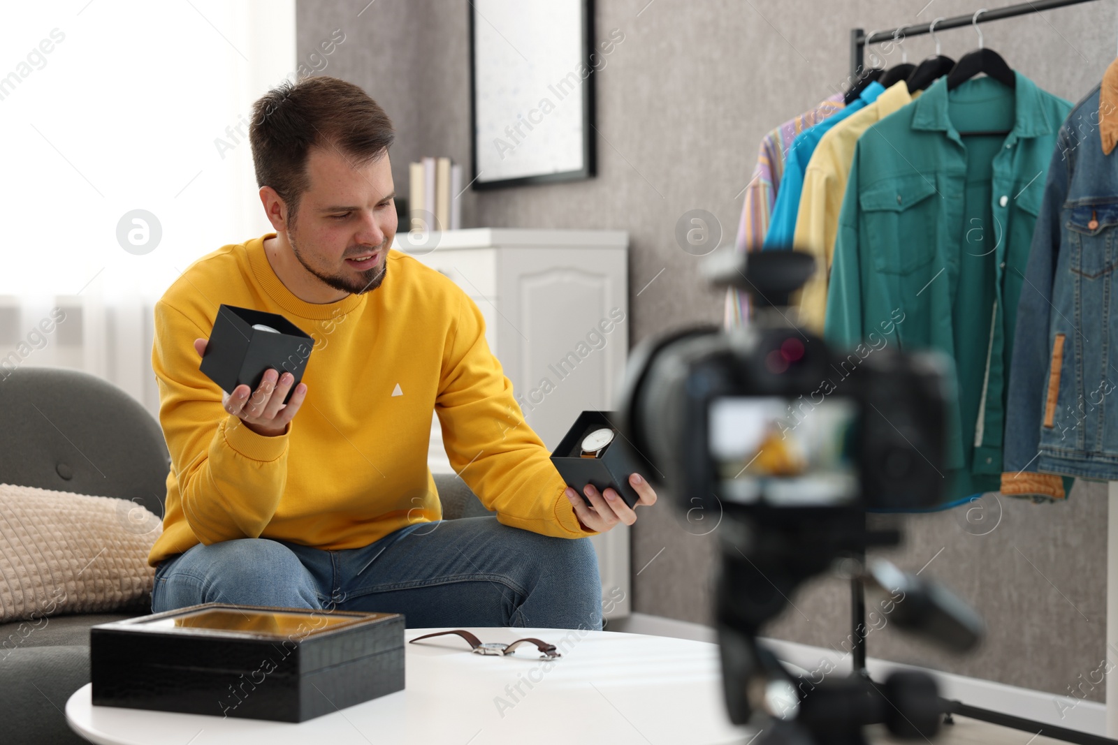 Photo of Fashion blogger showing wristwatches while recording video at home