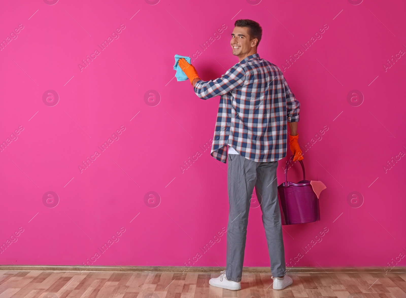 Photo of Man in gloves cleaning color wall with rag