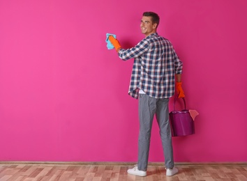 Photo of Man in gloves cleaning color wall with rag