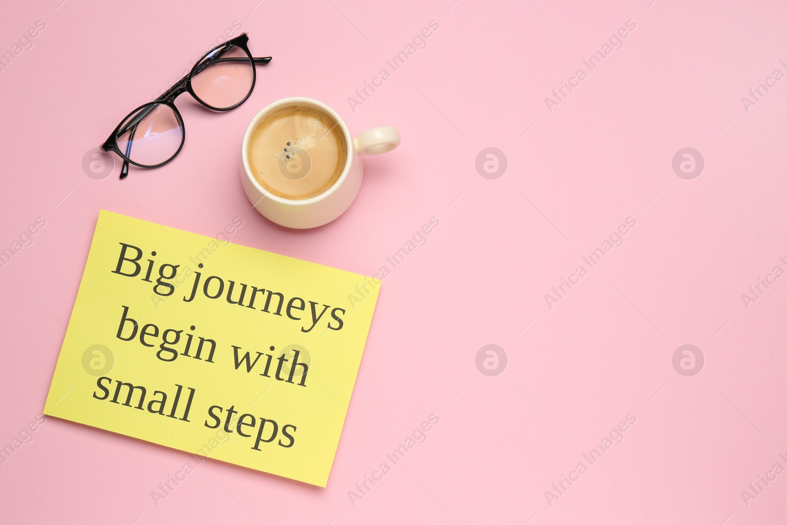 Photo of Motivational quote Big journeys begin with small steps, cup of coffee and glasses on pink background, flat lay. Space for text