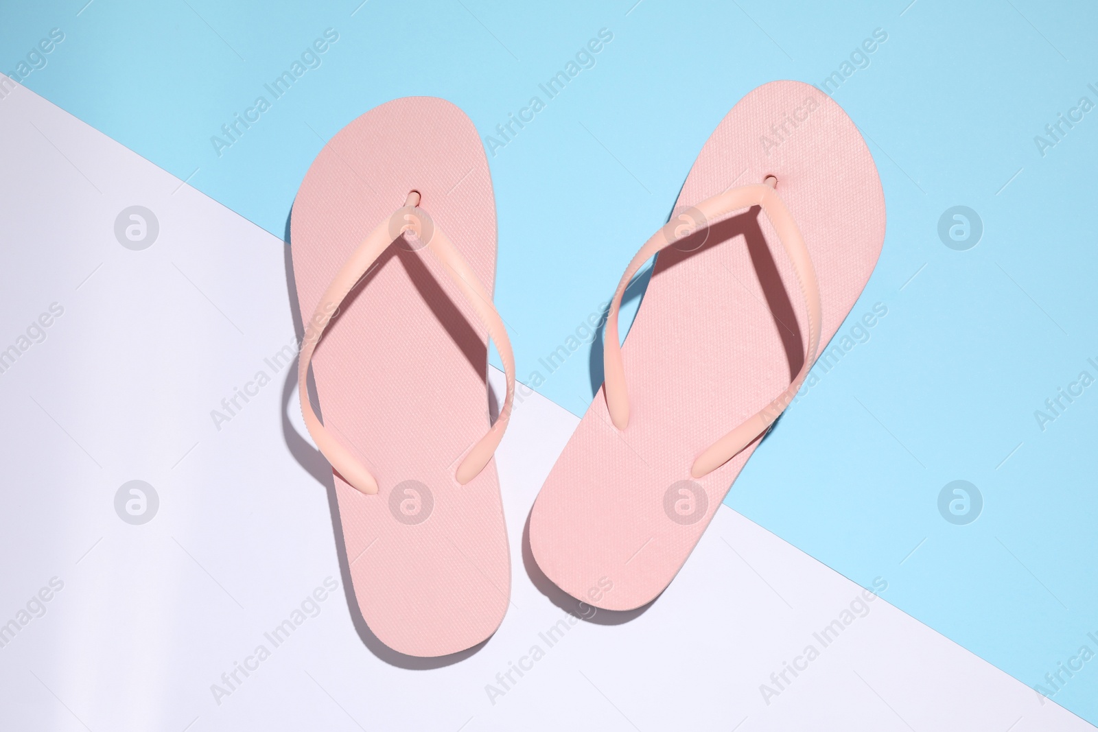 Photo of Pair of stylish flip flops on color background, top view. Beach objects