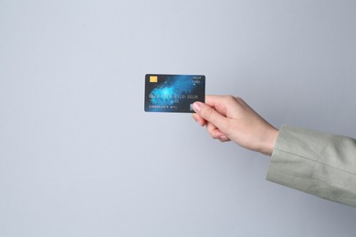 Woman holding credit card on light grey background, closeup