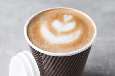 Coffee to go. Paper cup with tasty drink on grey table, closeup