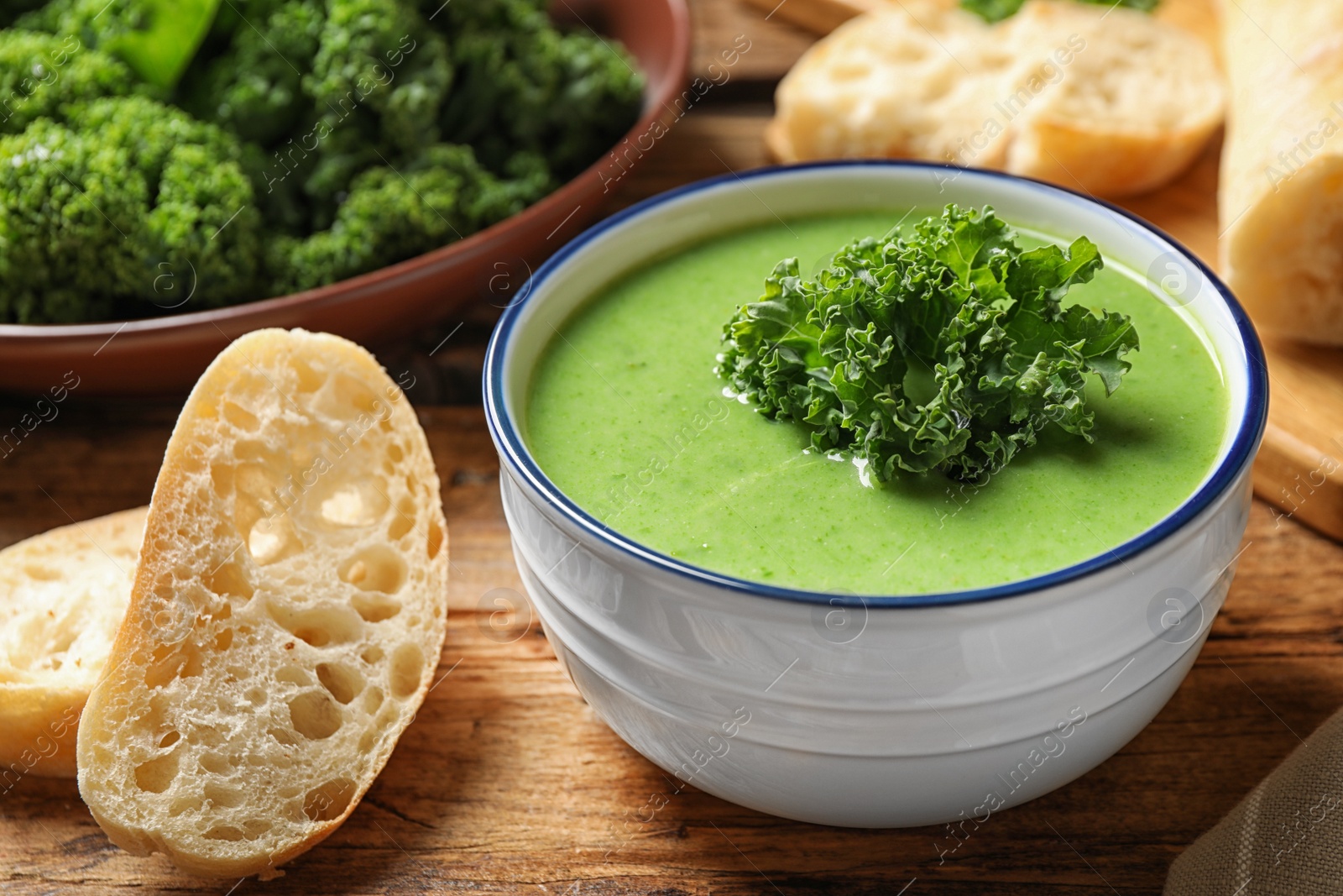 Photo of Tasty kale soup on wooden table, closeup