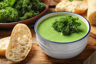 Photo of Tasty kale soup on wooden table, closeup