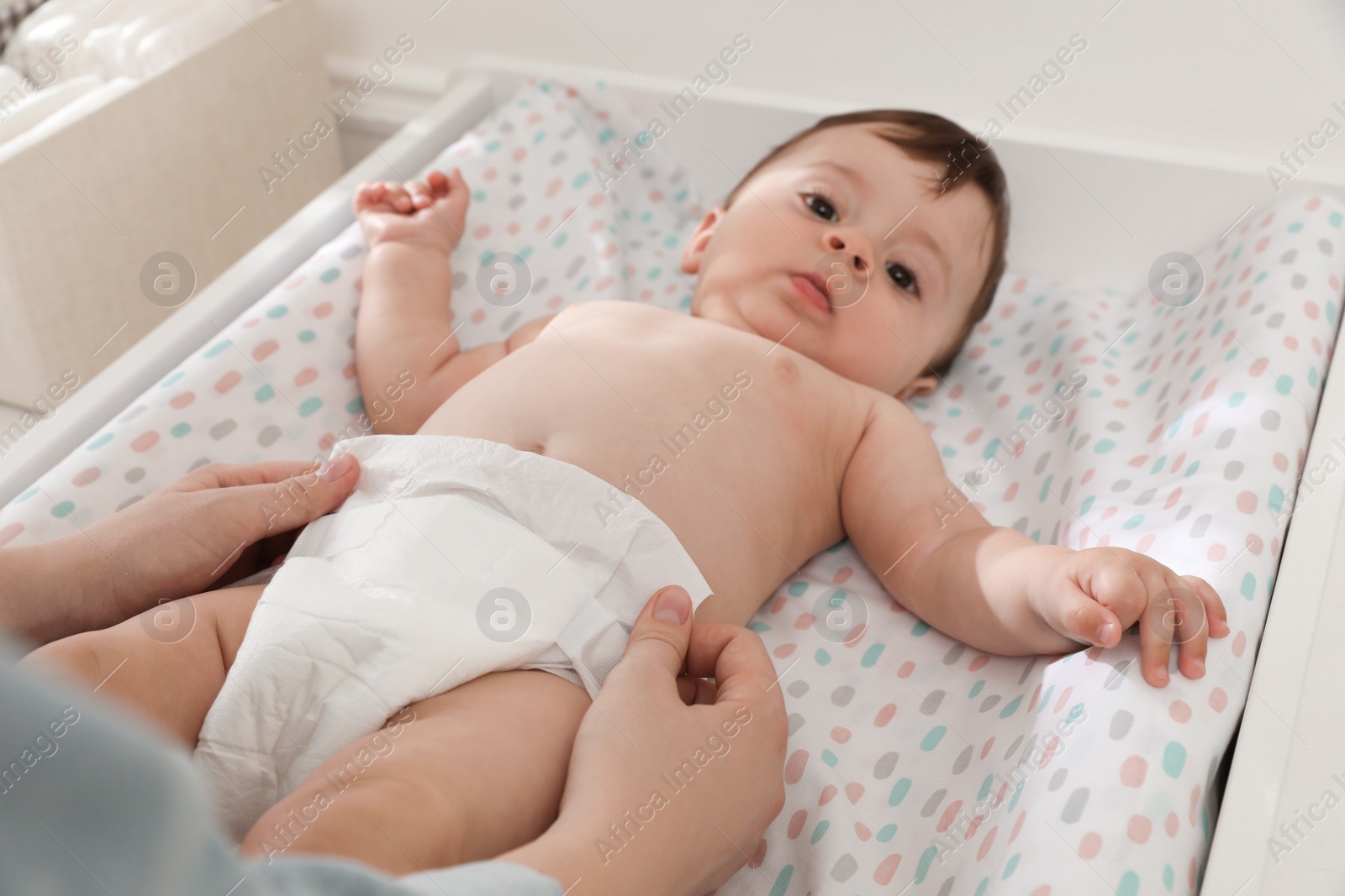 Photo of Mother changing baby's diaper on table at home, closeup