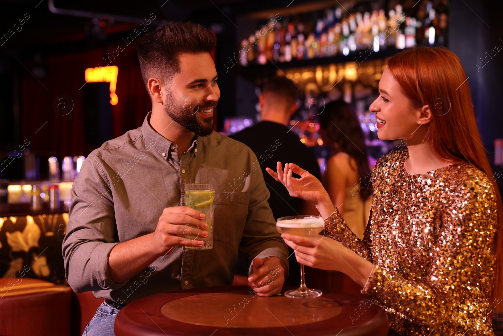 Photo of Happy couple with fresh cocktails at table in bar