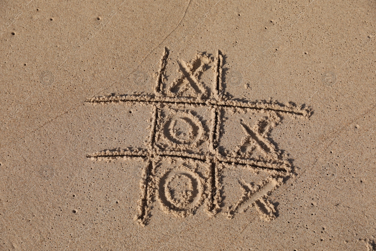 Photo of Tic tac toe game drawn on sandy beach, above view