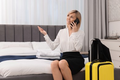 Photo of Smiling businesswoman talking on smartphone in stylish hotel room