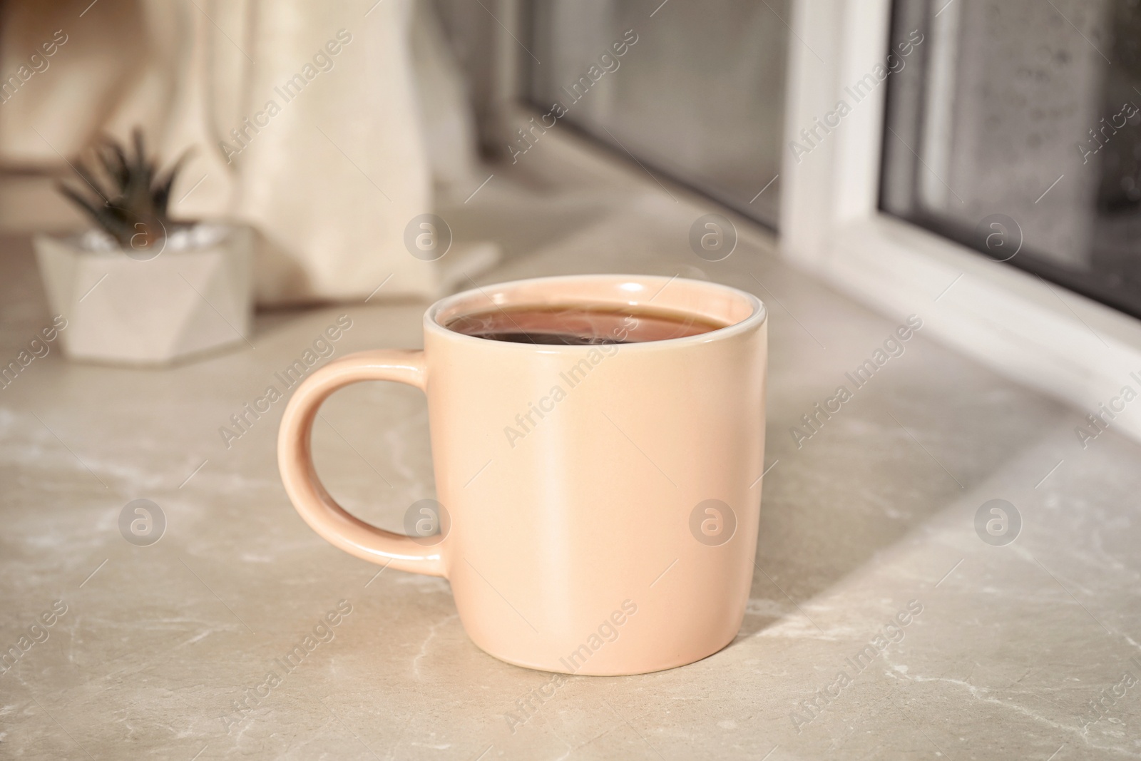 Photo of Cup of hot drink on window sill against glass with rain drops