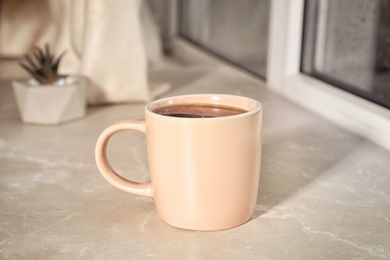 Photo of Cup of hot drink on window sill against glass with rain drops