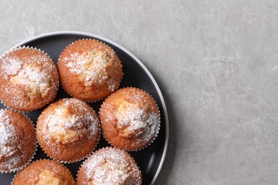 Delicious sweet muffins on light grey textured table, top view. Space for text