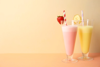 Photo of Glasses of tasty milk shakes and space for text on color background