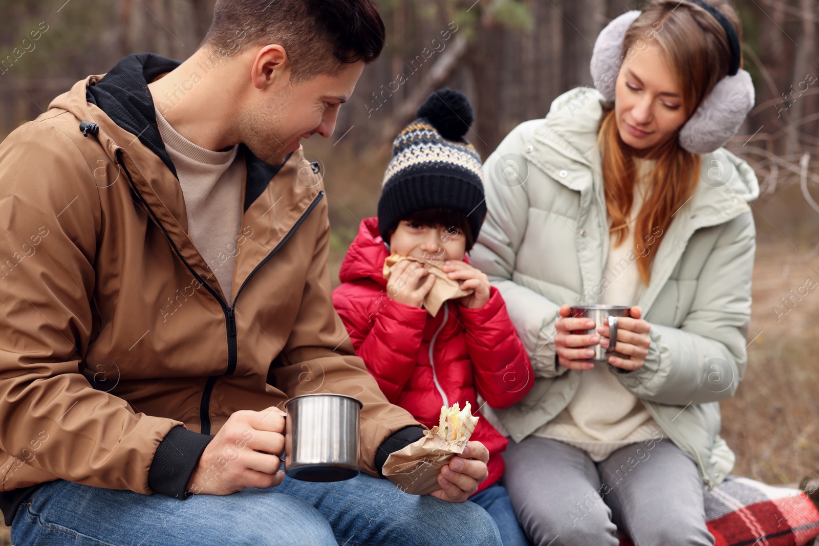 Photo of Happy family with sandwiches and hot drinks spending time together in forest