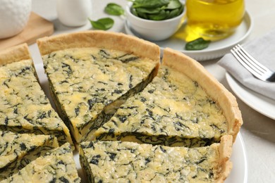 Photo of Plate of cut delicious spinach pie on light table, closeup