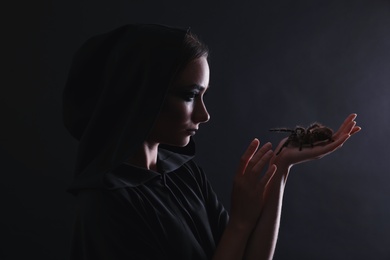 Photo of Mysterious witch with spooky spider on black background