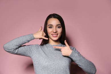 Photo of Woman showing CALL ME gesture in sign language on color background