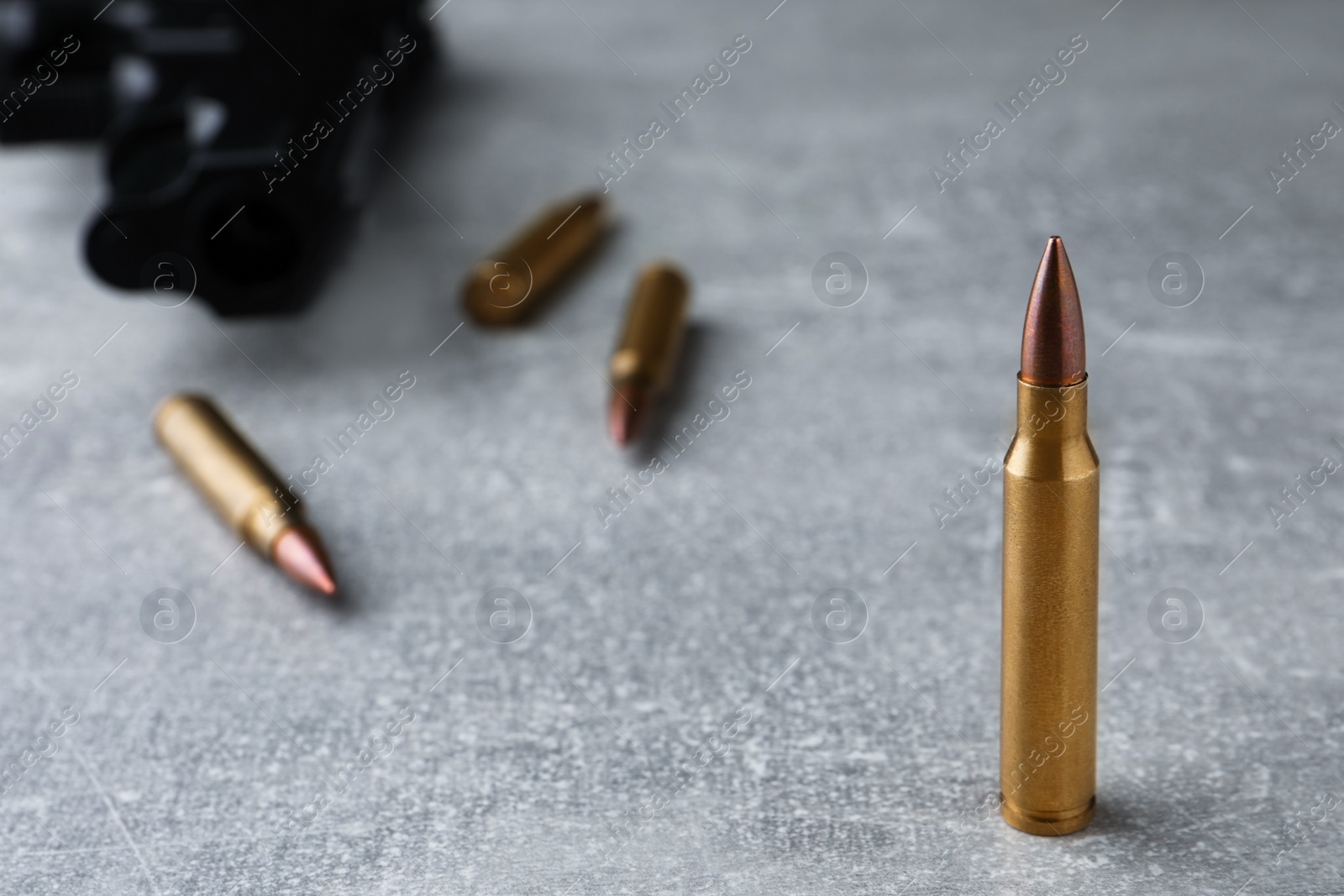 Photo of Bullets and handgun on light grey table, closeup. Space for text