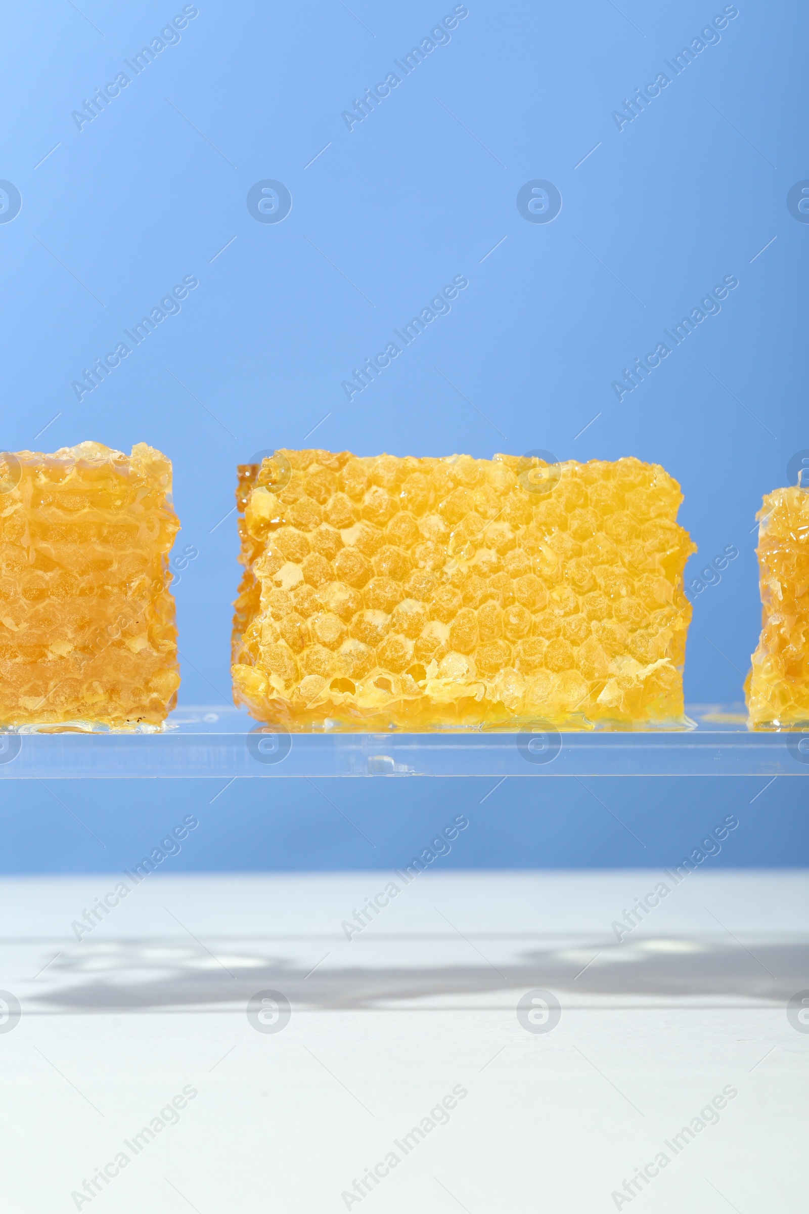 Photo of Natural honeycombs with tasty honey against light blue background