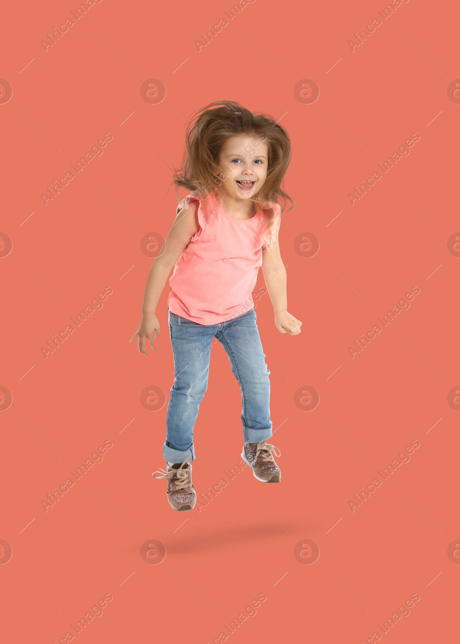 Image of Happy cute girl jumping on coral background