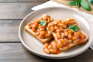 Toasts with delicious canned beans on wooden table, closeup