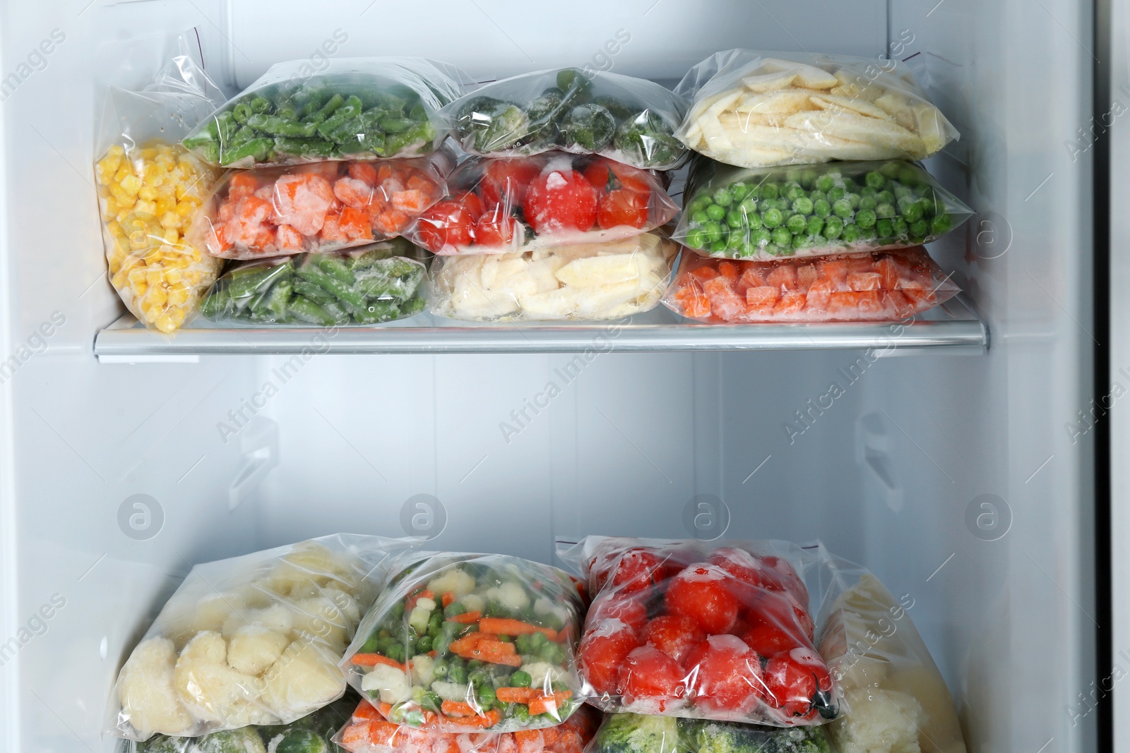 Photo of Plastic bags with different frozen vegetables in refrigerator