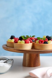 Delicious tartlets with berries on white table