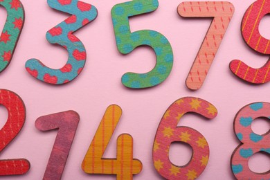 Photo of Colorful wooden numbers on pink background, flat lay