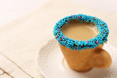Photo of Delicious edible biscuit cup of espresso decorated with sprinkles on table, closeup. Space for text
