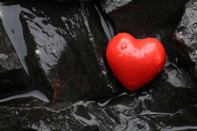 Photo of Red decorative heart on stones and water, top view. Space for text