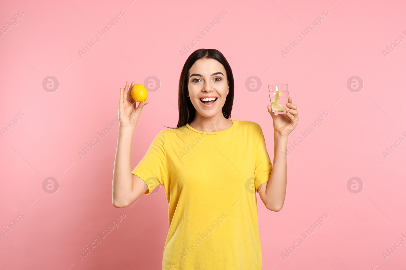 Photo of Beautiful young woman with tasty lemon water and fresh fruit on pink background