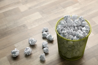 Photo of Metal bin with crumpled paper on floor, space for text