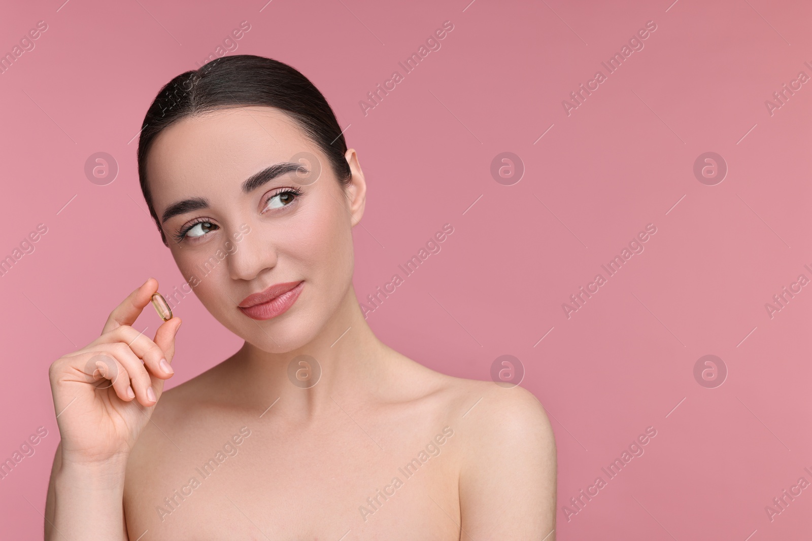 Photo of Beautiful young woman with vitamin pill on pink background. Space for text