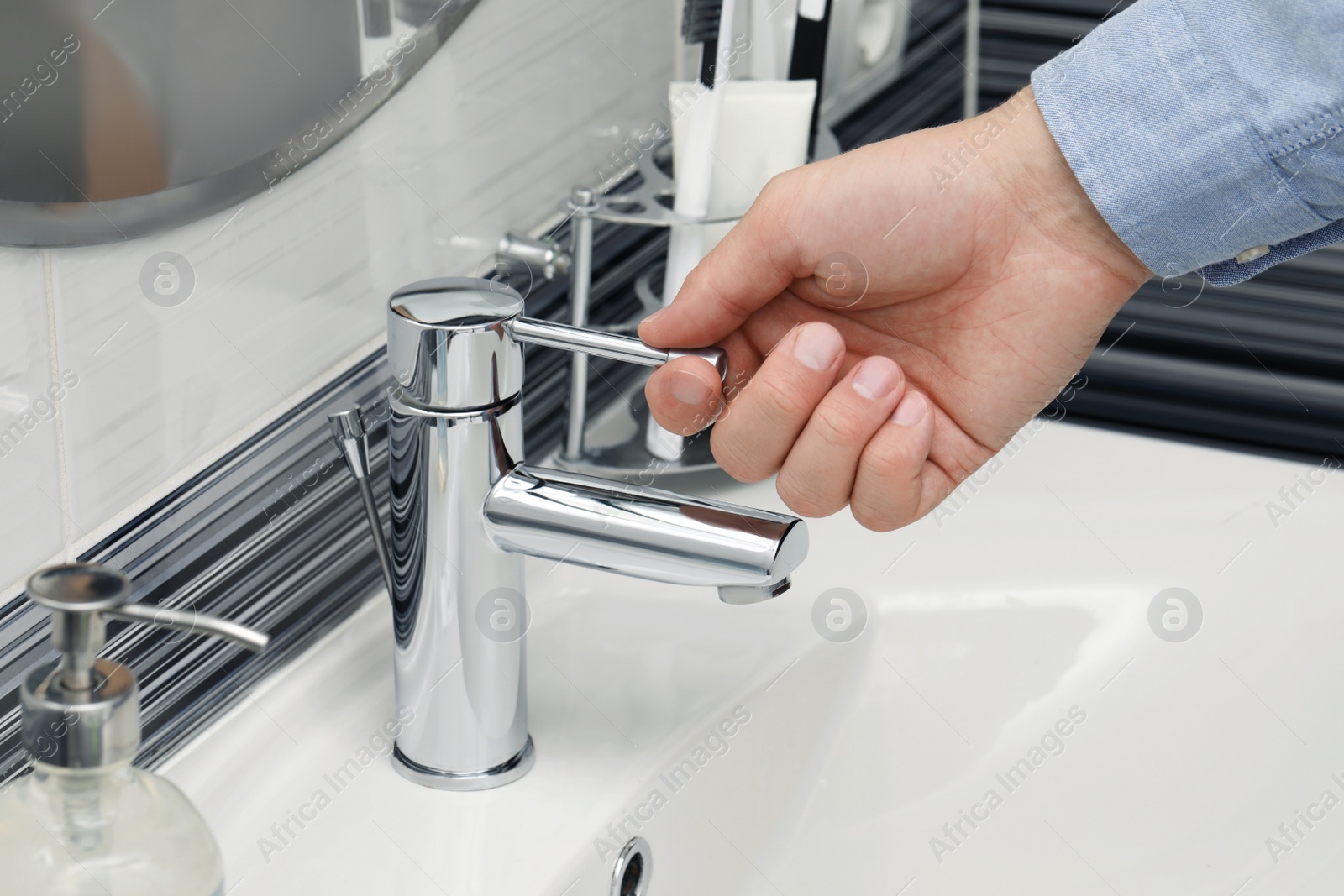 Photo of Man using water tap in bathroom, closeup
