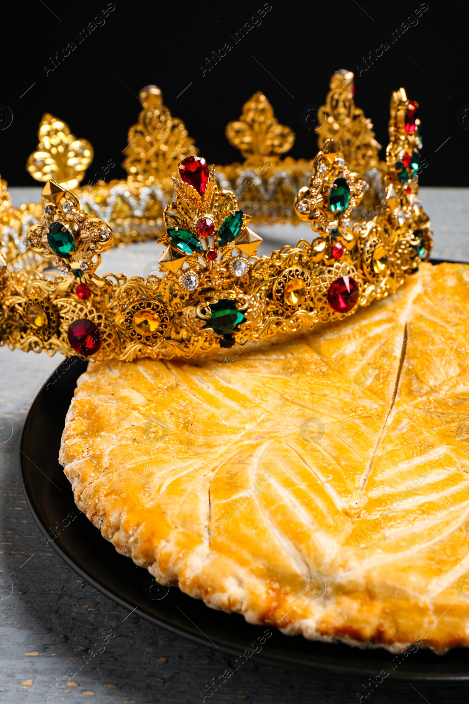 Photo of Traditional galette des rois with crown on grey wooden table, closeup