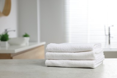 Photo of Stack of white towels on table in bathroom. Space for text