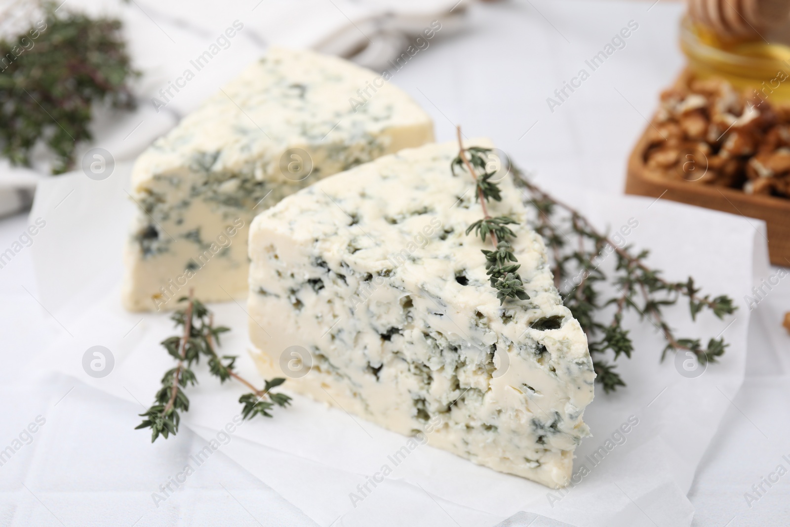 Photo of Tasty blue cheese with thyme on white table, closeup