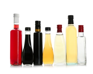 Bottles with different kinds of vinegar on white background